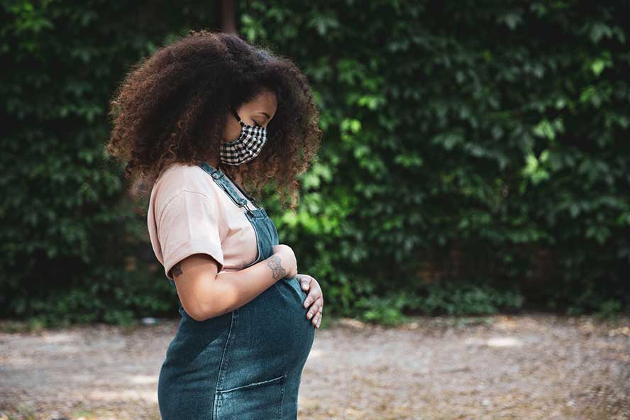 members-spd Pregnant woman looking down at her belly with her hands on it.