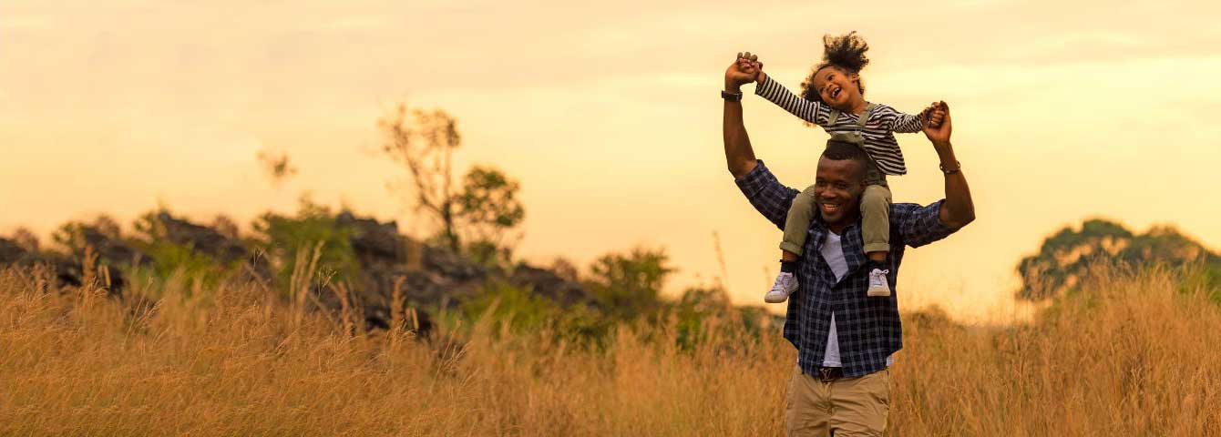 Father carrying daughter on shoulders in a wheat field