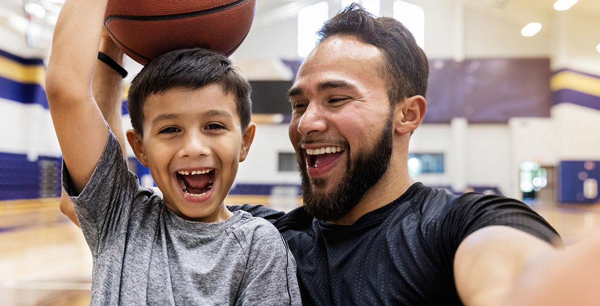 Dad and son playing on a basketball court