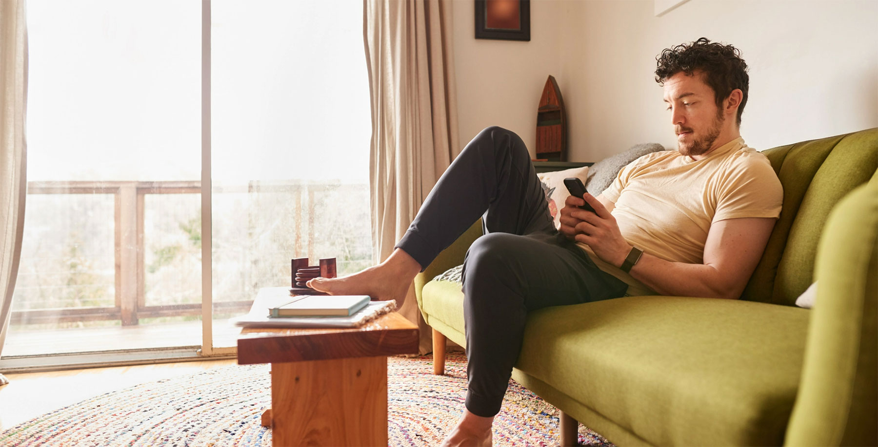 Man lounging on a pale green couching using his phone