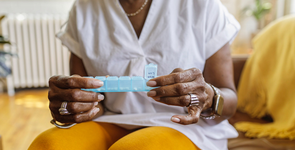 Person sitting on a couch holding a 7 day pill box