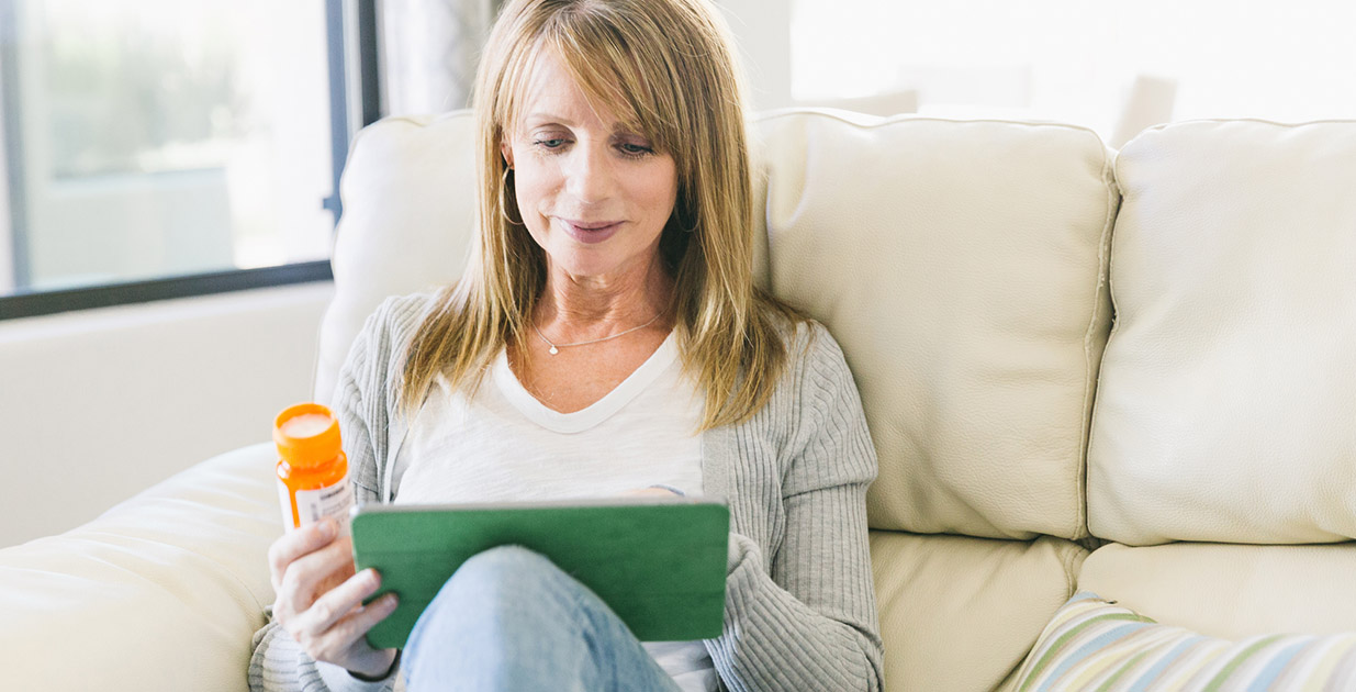 Woman checking her pill bottle and using an ipad