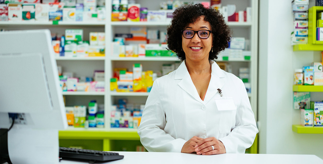 banner-savemoney Pharmacist standing behind the counter