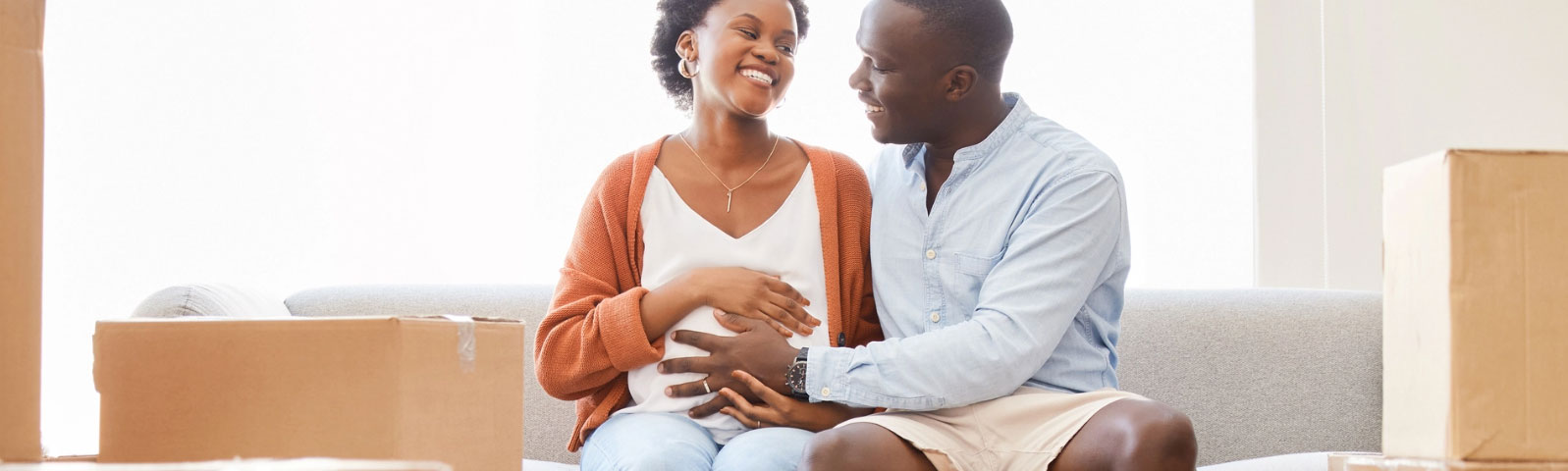 banner-sd-resources Couple sitting on a couch with the man holding his hand on the pregnant woman's stomach