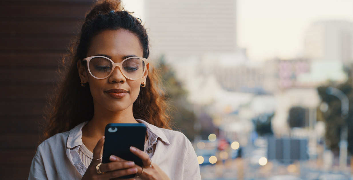 Young woman standing in front of window using her phone