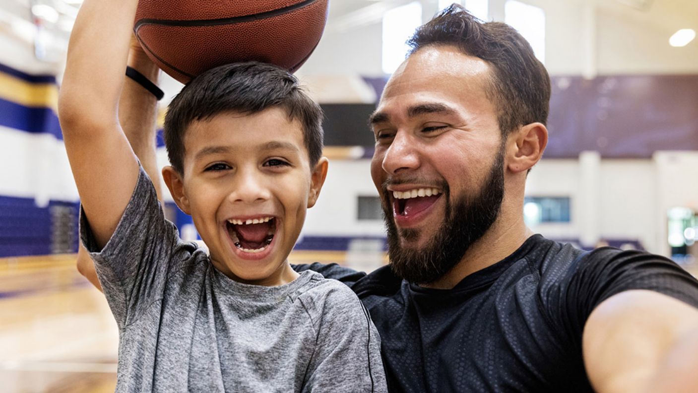 Dad and son playing on a basketball court