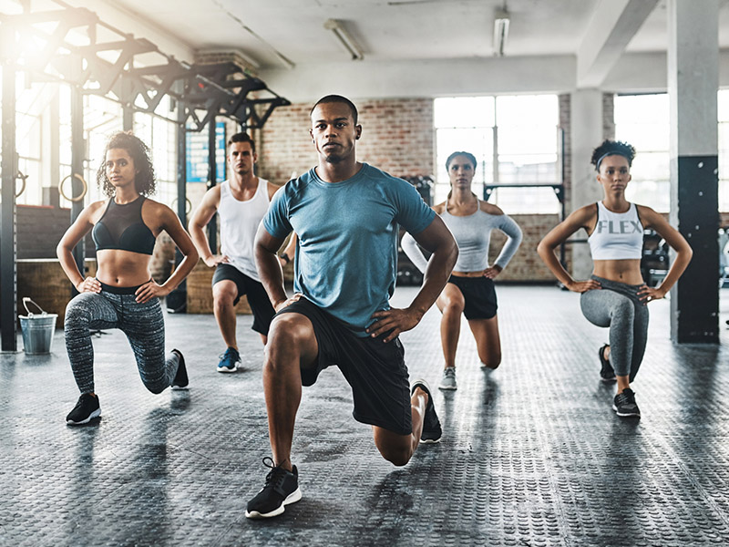 Group of people doing a lunge in a gym