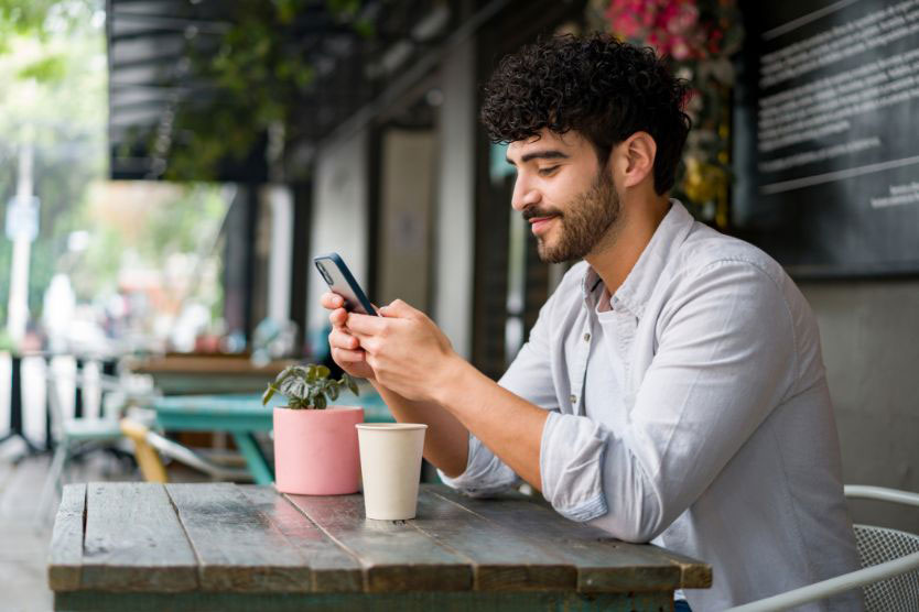 member-id-text Man sitting at a table looking at his cell phone