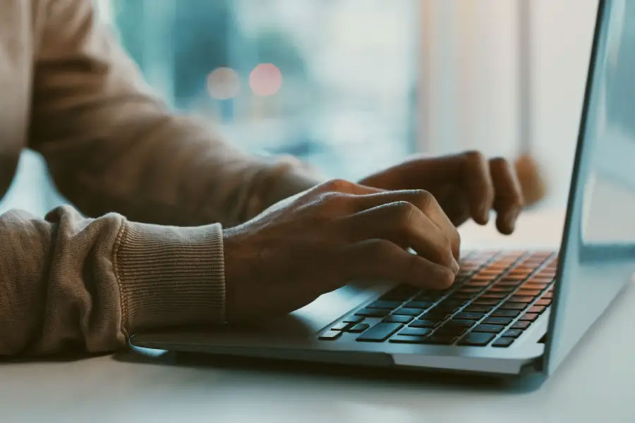 Hands typing on a laptop while at a desk