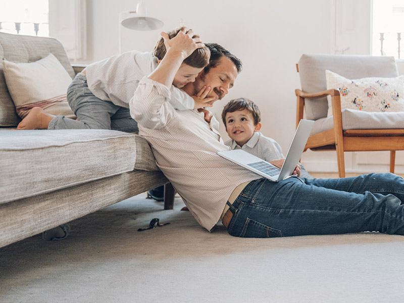 Father and two sons sitting in the living room floor using a laptop