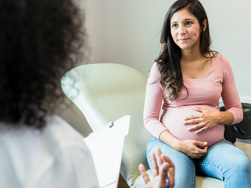 Pregnant woman sitting on a chair talking to her doctor