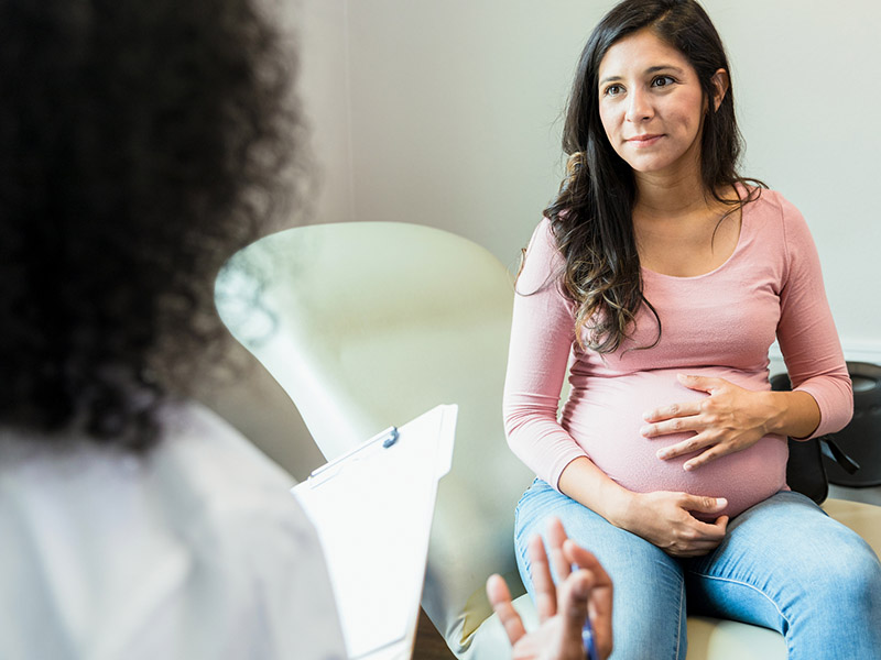 pregnancy Pregnant woman sitting on a chair talking to her doctor