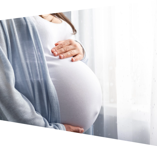 Pregnant woman holding stomach staring out a window