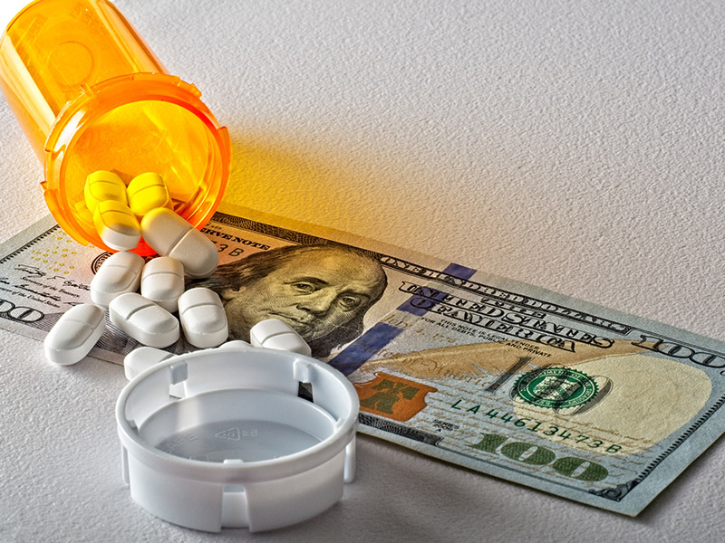 save money on meds 100 dollar bill with pill bottle on top of it