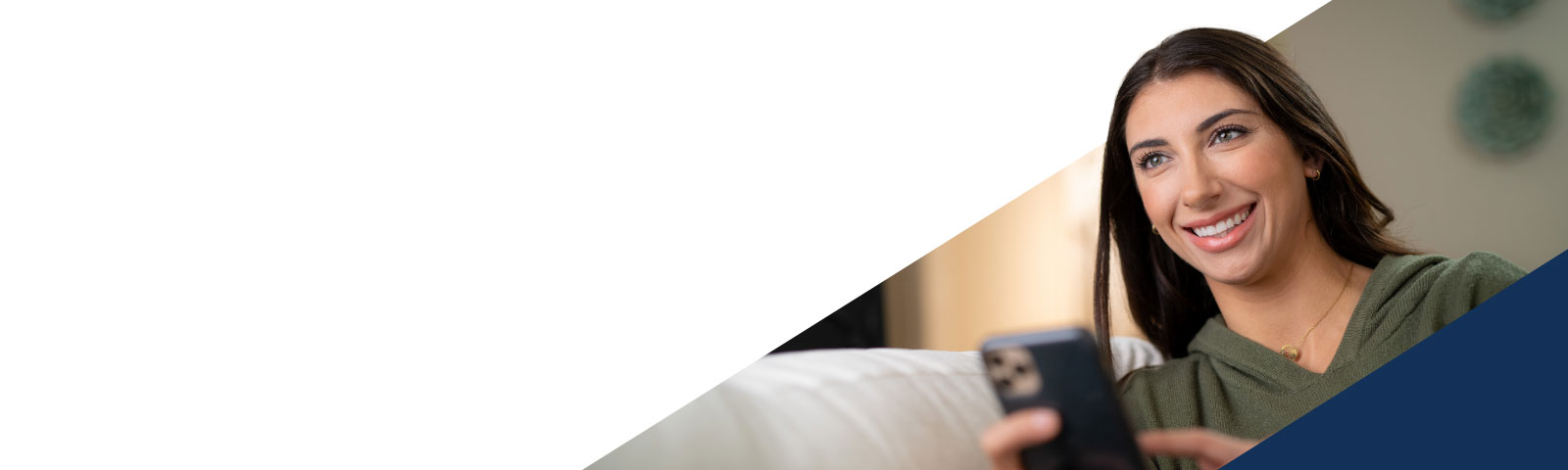Woman sitting on couch smiling and looking at her phone