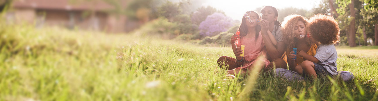 A family sitting in a field blowing bubbles