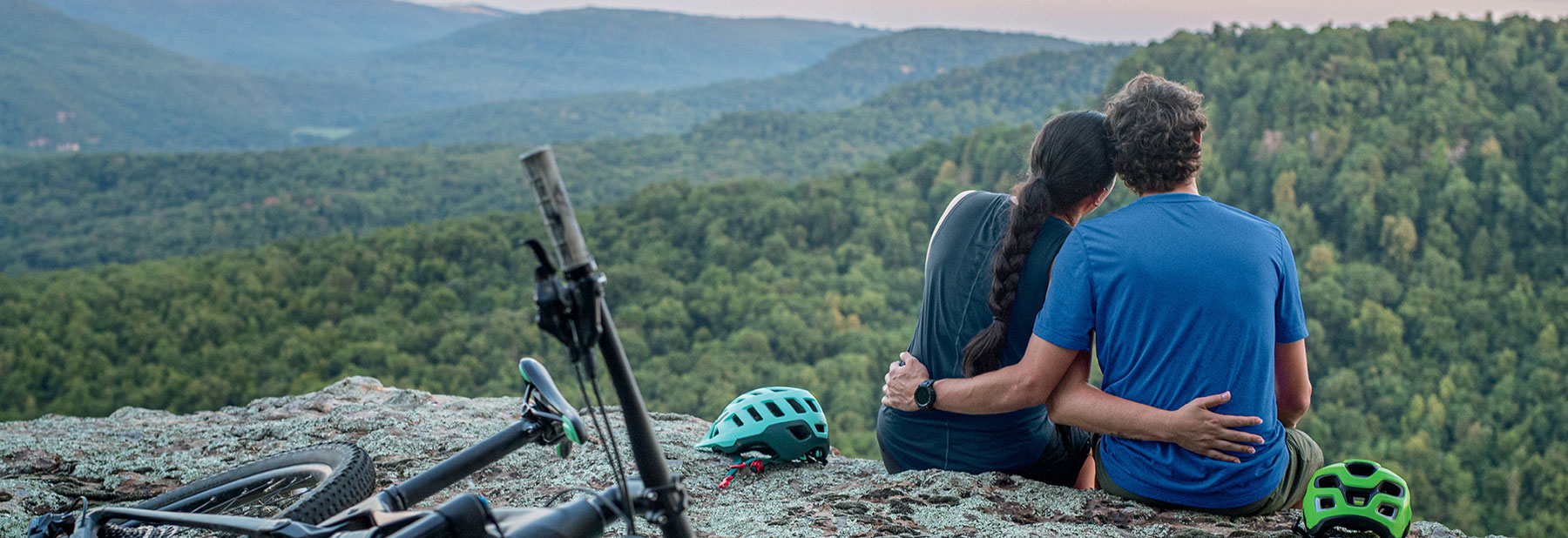 Couple sitting on cliff edge together.